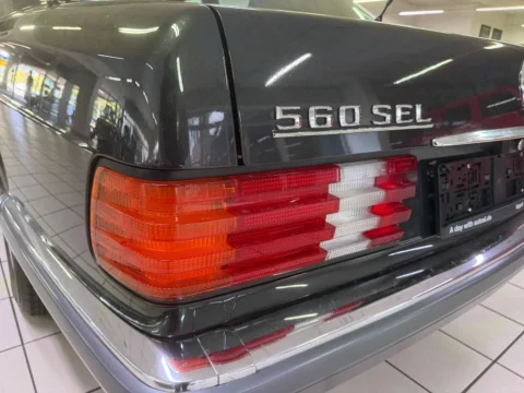 Mercedes-Benz 560 SEL — Задний фонарь Mercedes-Benz 560 SEL рядом с эмблемой на крышке багажника Mercedes-Benz 560 SEL: задний фонарь Mercedes-Benz 560 SEL рядом с эмблемой на крышке багажника